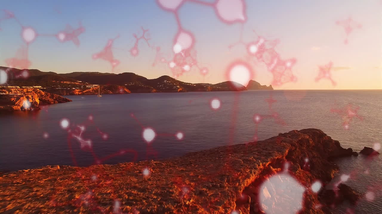 Animating red molecular structures over coastal landscape during sunset scene