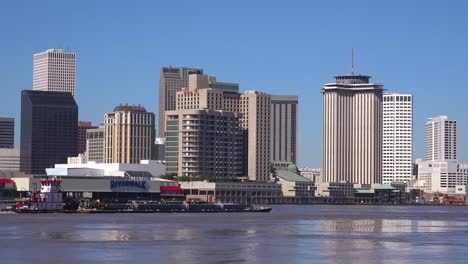 establishing shot of the city of new orleans with barges on the mississippi river foreground