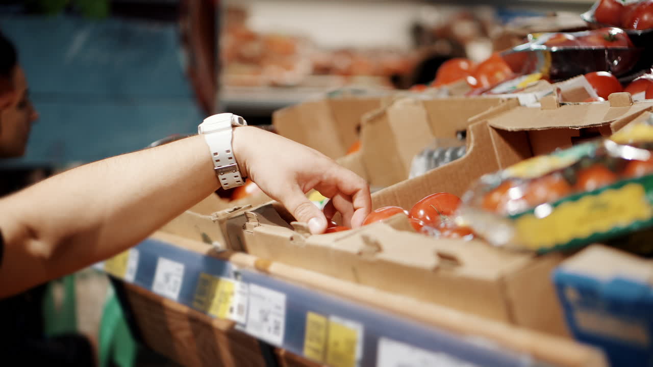 persona recogiendo tomates en una tienda de comestibles