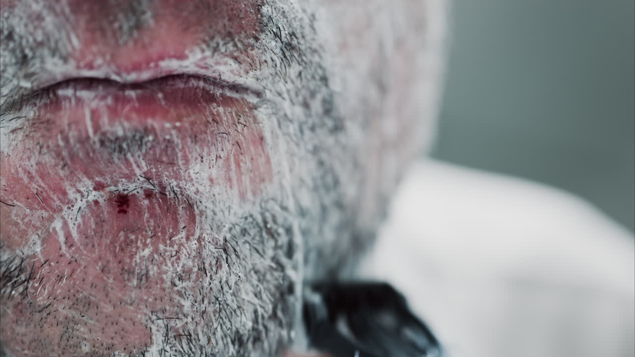 Close up of a man shaving his beard with a razor