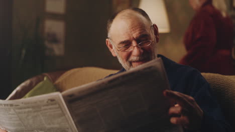 elderly man reading newspaper at home