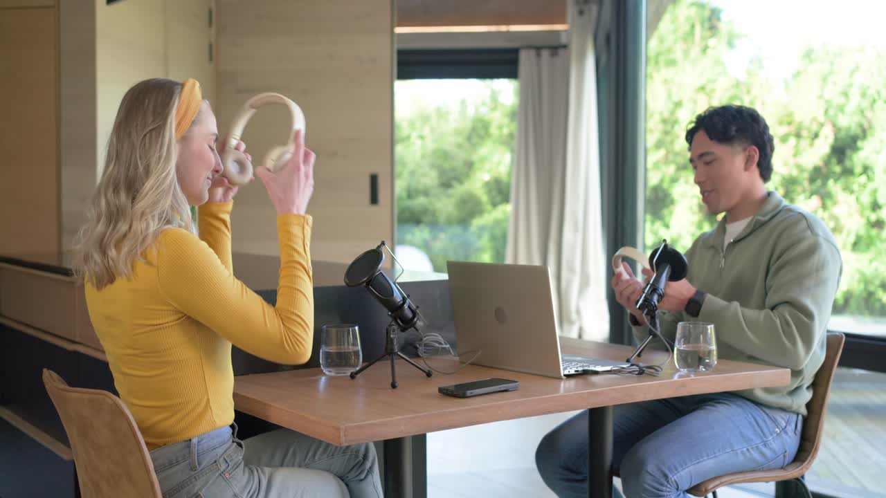 Diverse coworkers shaking hands, donning headphones, adjusting mics in studio for recording podcast