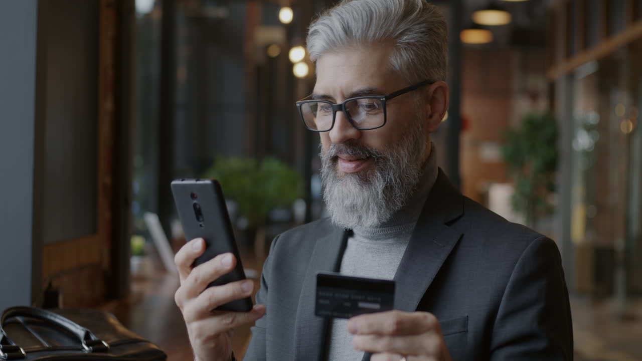 Businessman making a payment on his smartphone in a cafe