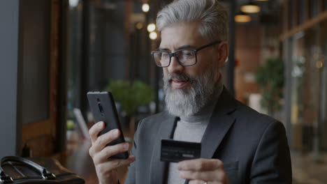 businessman making a payment on his smartphone in a cafe