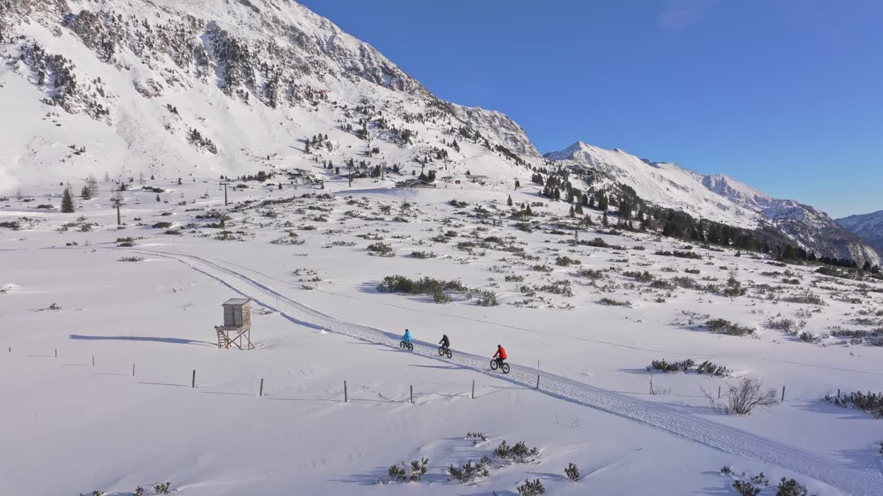 Vista aerea di ciclisti su fatbike che attraversano il paesaggio austriaco innevato