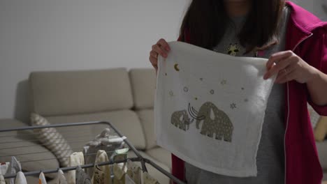 pregnant young woman hanging baby clothes on the clothesline.