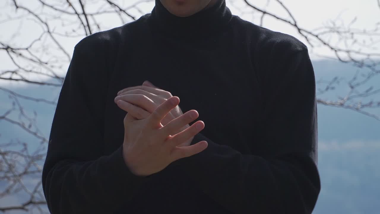 A man stretches his fingers gracefully against a backdrop of bare trees and rolling hills. Ideal for active outdoor lifestyle, adventure, and commercial projects.