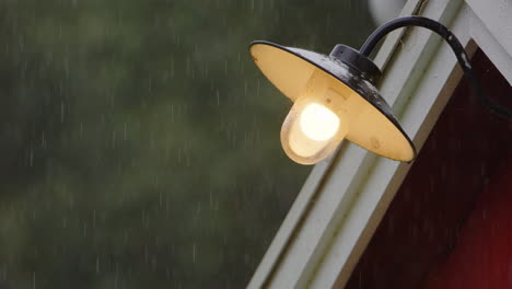 a porch lamp shines through slow motion rain