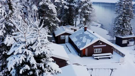 winter scenery with snow and cabins in norway - aerial pullback