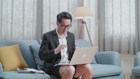 재과 쇼트를 입은 아시아 사업가 가 집 에서 노트북 으로 비디오 통화를 하고 있다