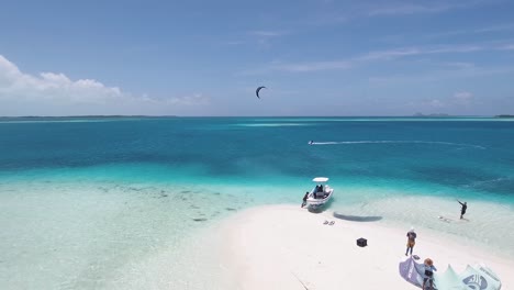 kitesurf camp in white sand beach atoll with boat an two men flying, los roques