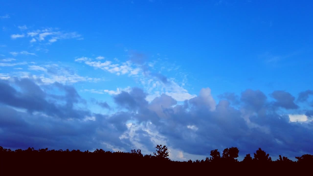 Time-lapse during sunset. Mesmerising black and white cloud movement in blue sky on f forest line. HD