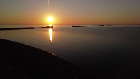 hermosa puesta de sol aérea vibrante de alto contraste sobre el tranquilo mar báltico, muelle de roca en el puerto de liepaja , disparo de drones de gran angular que avanza lentamente con zoom