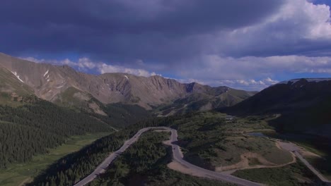 cars driving around hairpin turn winding rocky mountain pass drone 4k