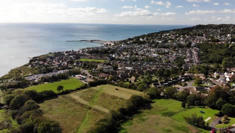 Antena-Sobre-Campos-Con-Vista-De-La-Ciudad-De-Lyme-Regis-En-Segundo-Plano.