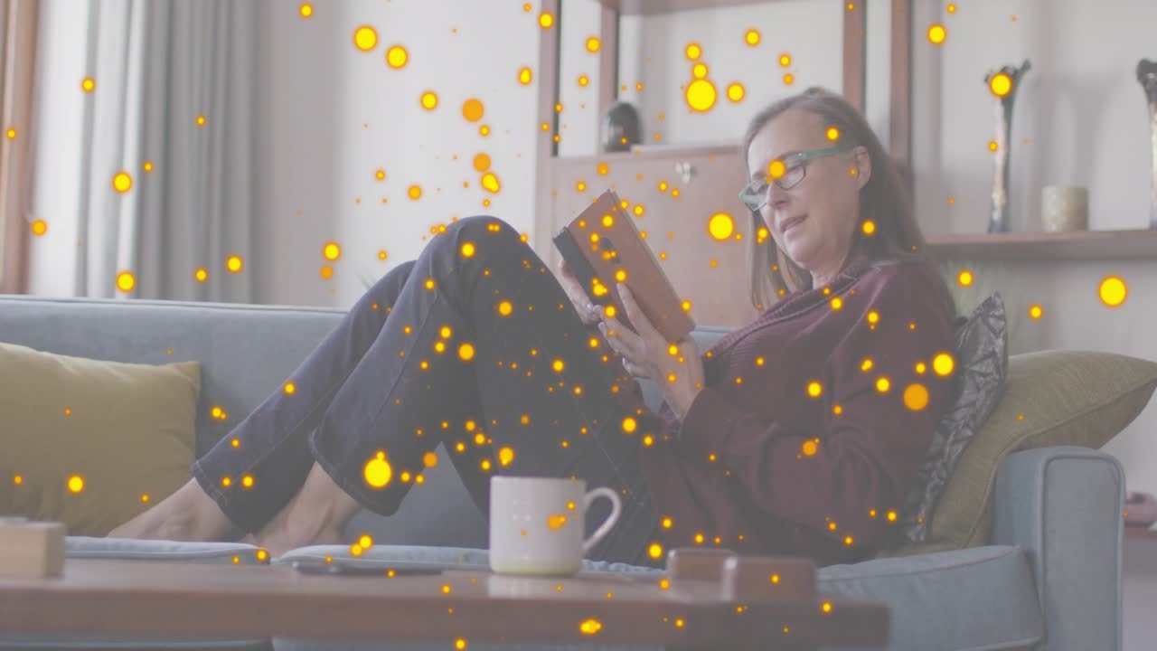 여자가 회색 소파에서 책 페이지를 펼치자 몰입형 학습을 위한 빛나는 입자들이 뿜어져 나오고 있어요.