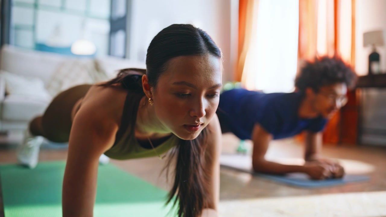 Multiethnic couple holding plank position home workout. Fitness training.