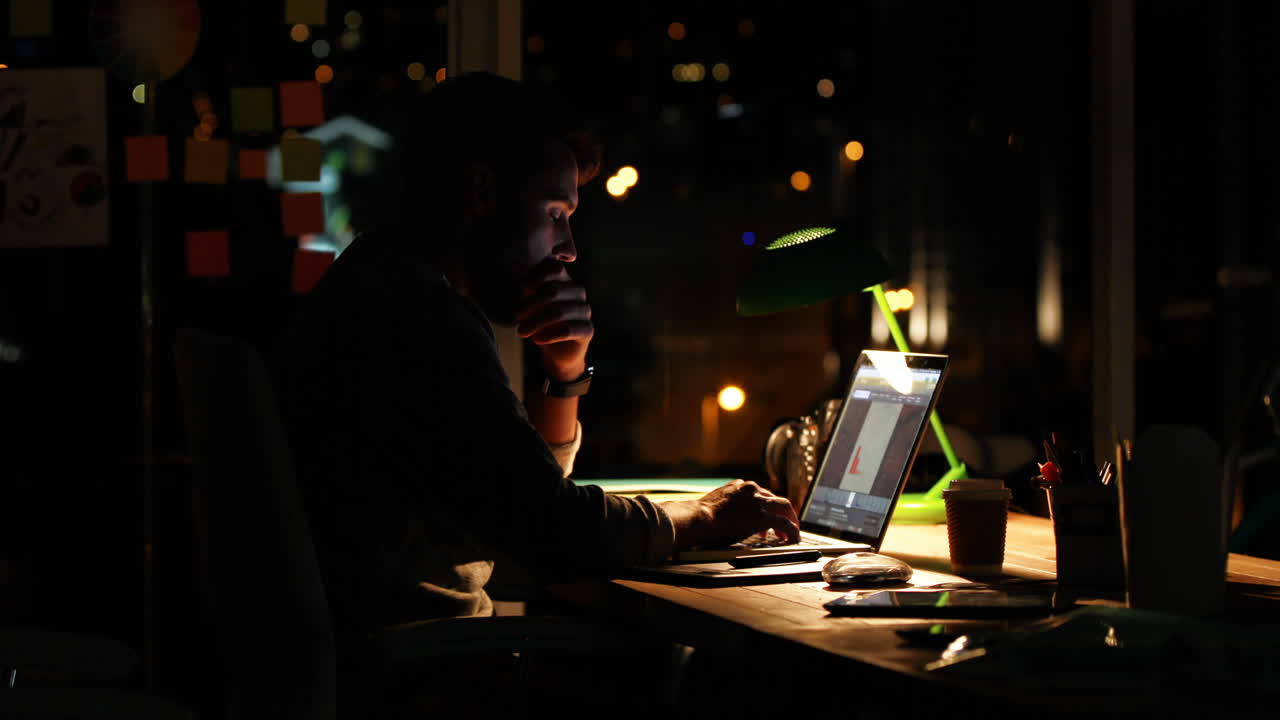 Uomo d'affari informale che utilizza un portatile di notte