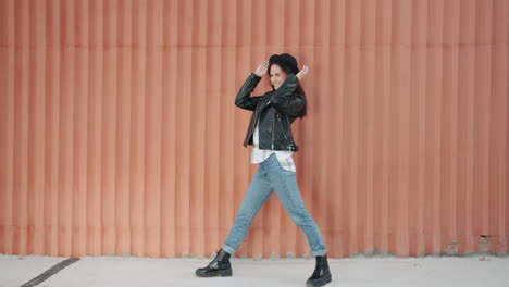 stylish woman posing in front of an orange wall