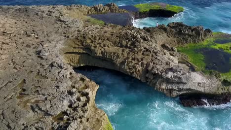 Hermosa-Vista-Aérea-Vuelo-Sobrevuelo-Drone-Disparó-Grandes-Olas-Del-Océano-Rompiendo-En-Las-Rocas-De-La-Lágrima-Del-Diablo-En-Lembongan-Indonesia-Rock-Cliff-Beach-Al-Mediodía-Bali-2017