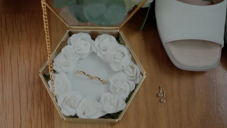 wedding rings and accessories: closeup of gold wedding bands, white roses, and bridal shoes