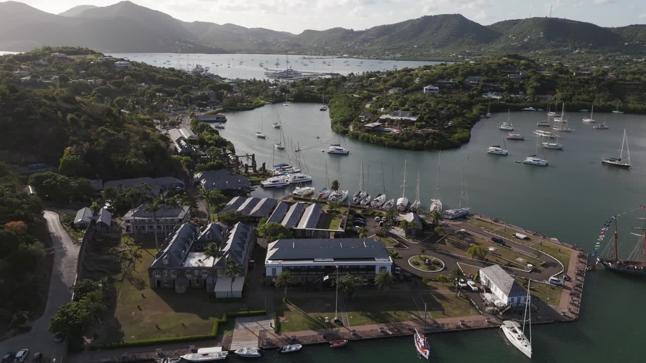 Scenic aerial view of English Harbour in Antigua with boats, hills, and lush greenery in the evening light