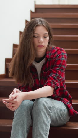 woman with negative emotions sits on staircase. lady with mental health problems chooses place to be alone at home. depression disorder symptoms