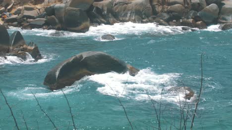 waves crashing against a rock in slow-motion in the blue ocean of tayrona park, colombia