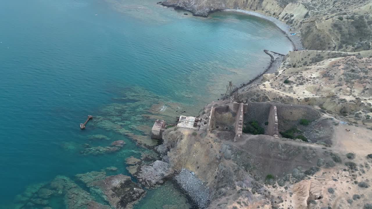 mirando hacia abajo desde arriba, somos testigos de los restos abandonados de una mina de hierro abandonada y un puerto costero en ruinas