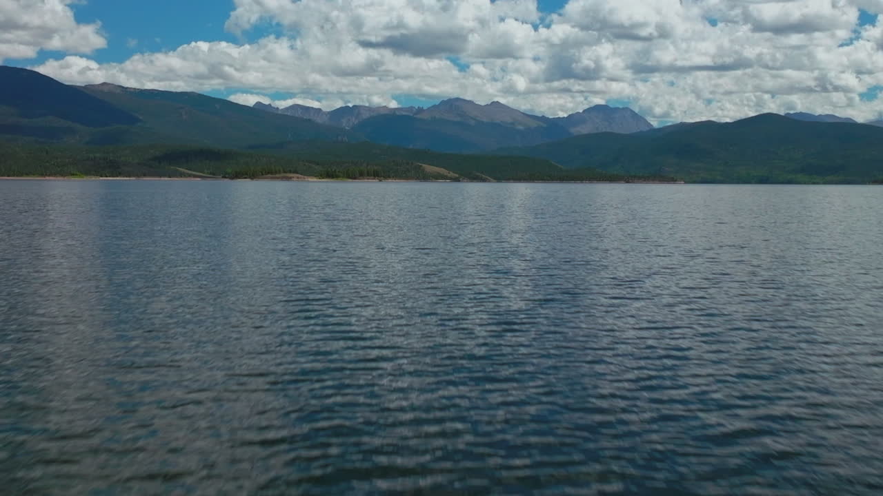 avión no tripulado cinematográfico de alta altitud gran lago sombra montaña abuelo colorado montañas rocosas entrada del parque nacional ondas tranquilas hermosa mañana de verano navegación dos islas hacia adelante revelar movimiento