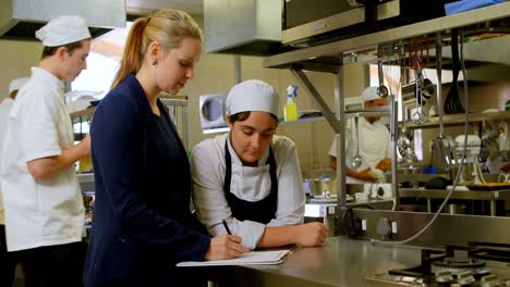 female manager and female chefs discussing over clipboard 4k