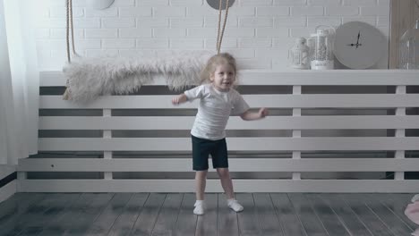 toddler girl in white t-shirt does physical exercises