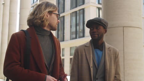 two multiethnic businessmen walking on street and talking