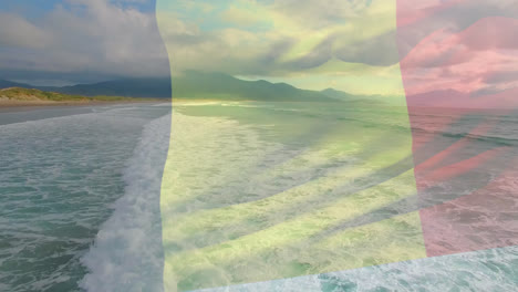 animation of flag of belgium waving over beach landscape, sea and cloudy blue sky