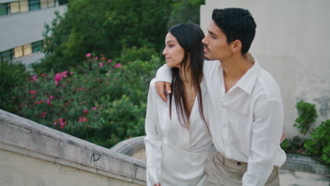 embracing spouses crossing stairs at town. relaxed man kissing loving cute woman