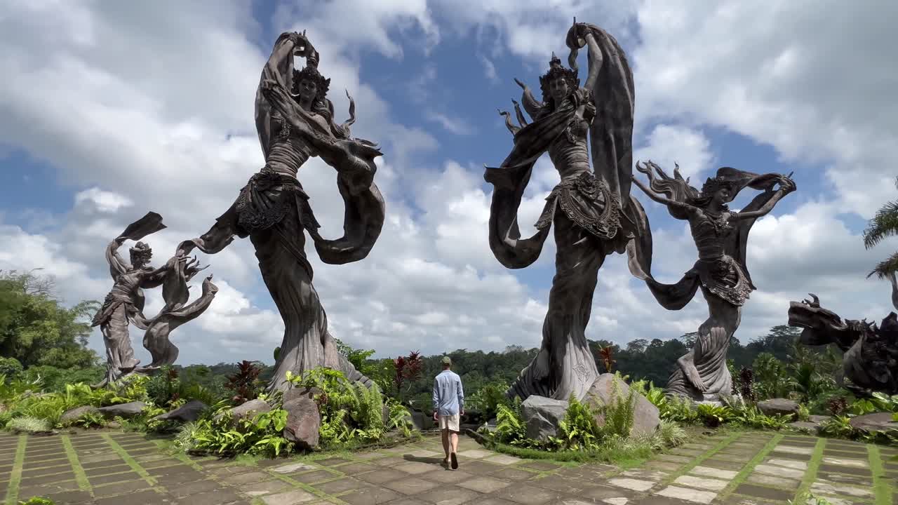 Huzuru Keşfetmek: Genç turist, Ubud, Bali'deki Taman Dedari Restoranı'nda melek heykellerine yaklaşıyor - 4K Gimbal İleri İtme Çekimi