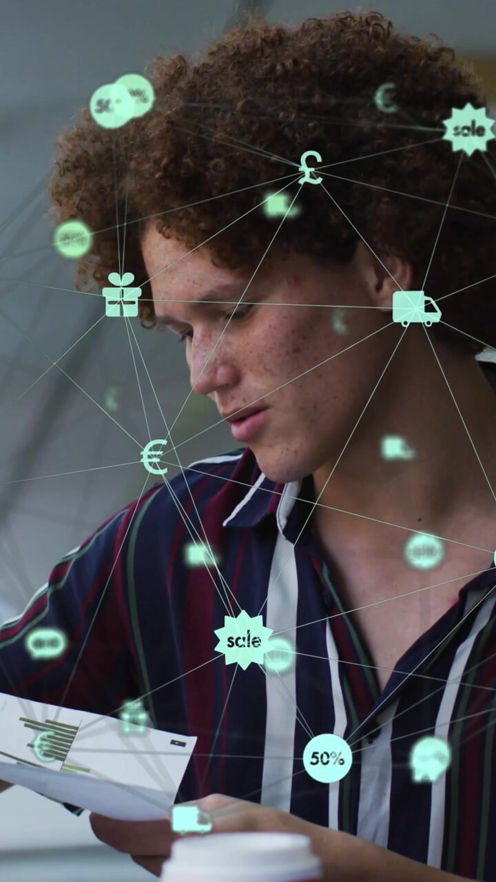 Animation of globe of digital icons over two diverse male office colleagues discussing over document