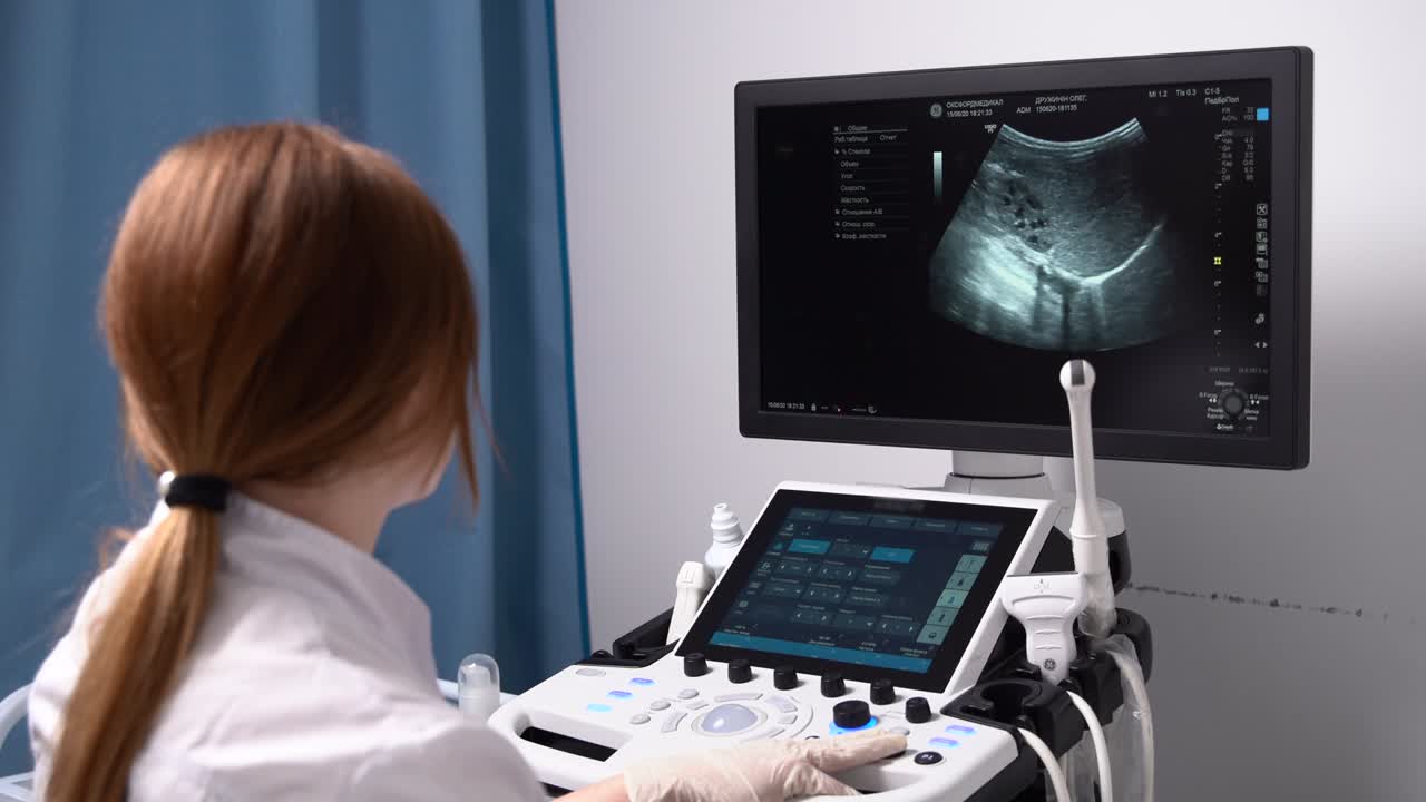 Una dottoressa con mascherina e guanti guarda lo schermo dell'ecografia in una clinica moderna. Diagnosi del paziente. Medicina
