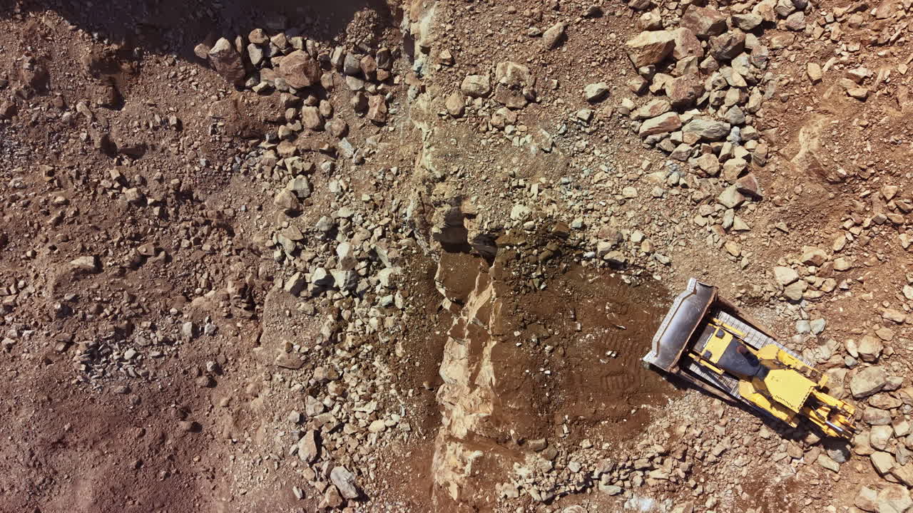 Macchinari pesanti lavorano in un cantiere in una zona montuosa con rocce e terra durante il giorno
