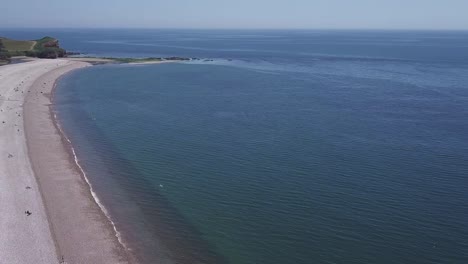 Flying-out-towards-the-curved-seashore-in-Devon,-UK,-AERIAL-STATIC-CROP