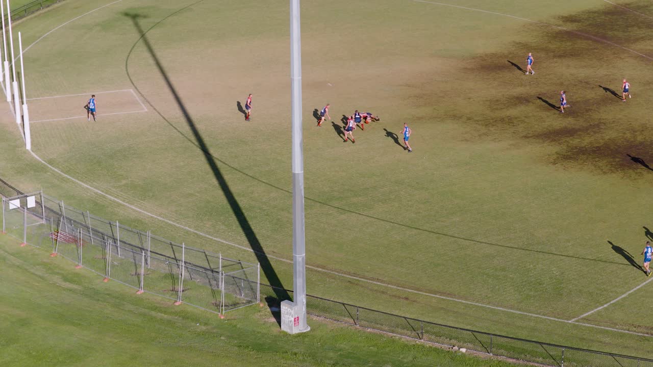 Aerial footage captures a dynamic Aussie Rules football game on a sunny day in Gold Coast, Australia