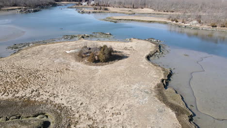 Slow-aerial-flight-over-mudflats,-showing-brackish-water-and-the-salt-marshes