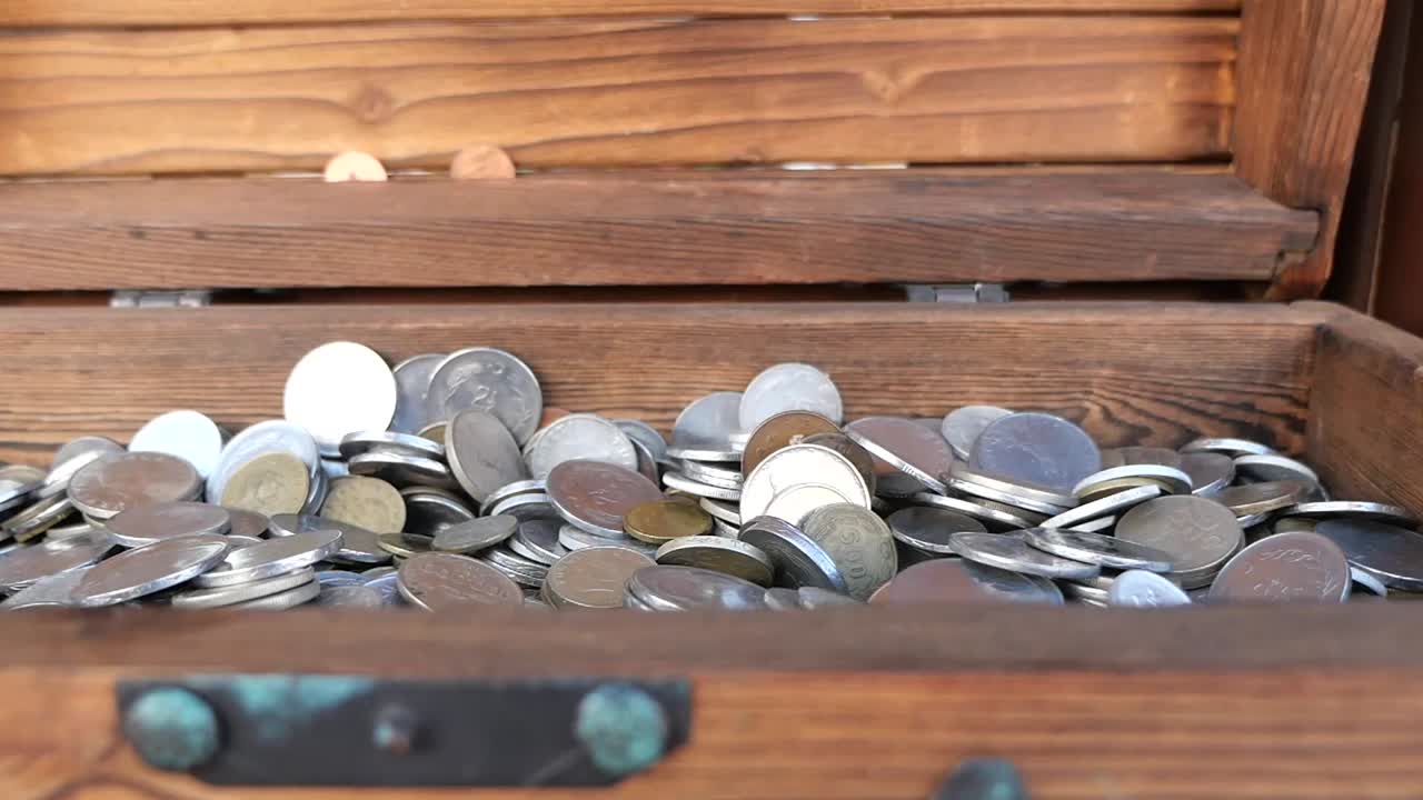 Des pièces tombant dans un coffre au trésor en bois
