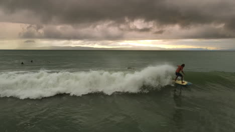el vasto océano contrasta con los surfistas solitarios, destacando la magnitud de la naturaleza.