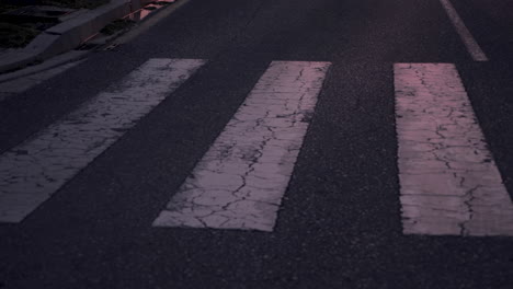 nahaufnahme eines athleten, der in der abenddämmerung einen zebrastreifen überquert und in der stadt läuft