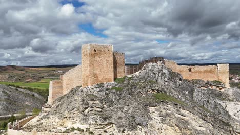 Aerial-spinning-drone-view-of-a-medieval-castle-in-Burgo-de-Osma-village-in-Soria,-Spain