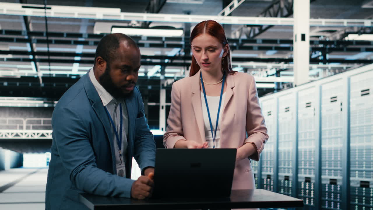 IT Technicians Discussing Data on Laptop in Server Room