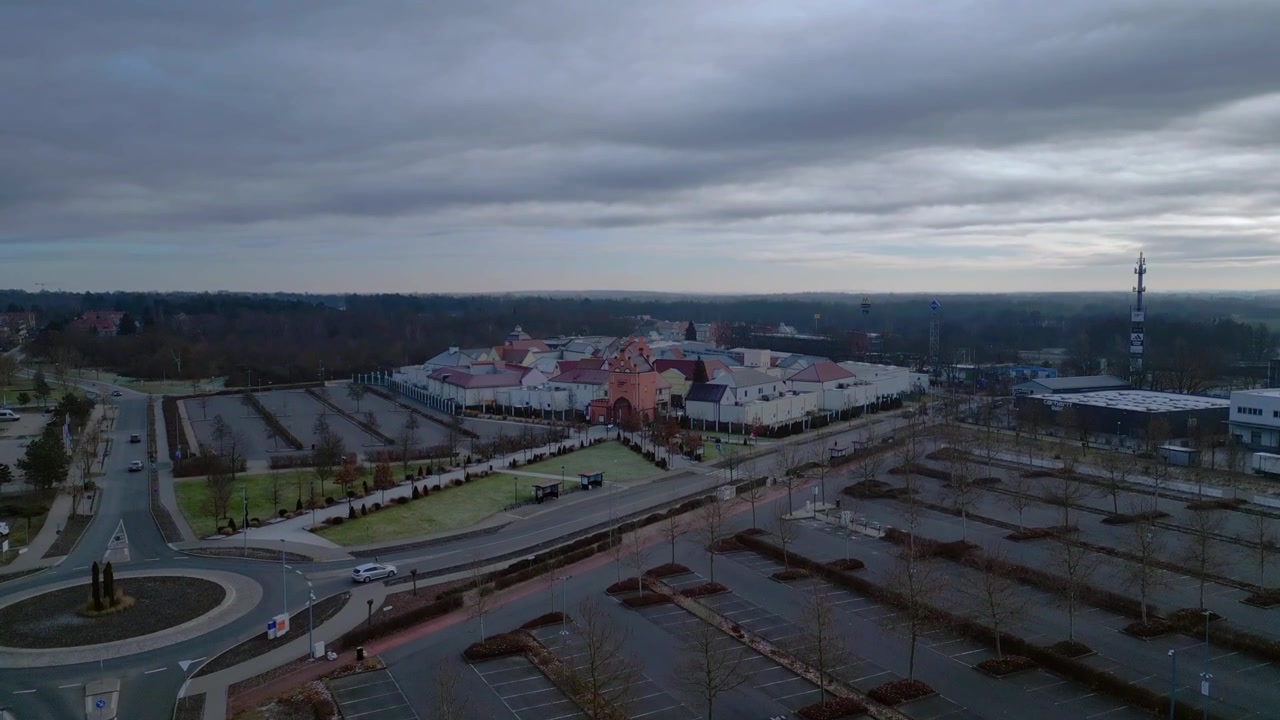 Drohnenansicht eines großen Einkaufs- und Fachmarktzentrums mit verschiedenen Geschäftsgebäuden und einem Haupteingangstor im Winter. Atemberaubende aufsteigende Panorama-Drohnenaufnahme.