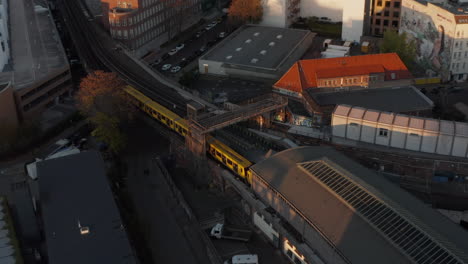 Scenic-Aerial-View-of-Yellow-Train-entering-Subway-Station-elevated-above-ground-in-Berlin,-Germany