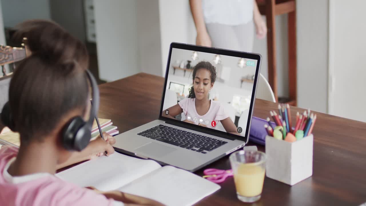 composición de una colegiala afroamericana en una computadora portátil aprendiendo en línea con una colegiala biracial